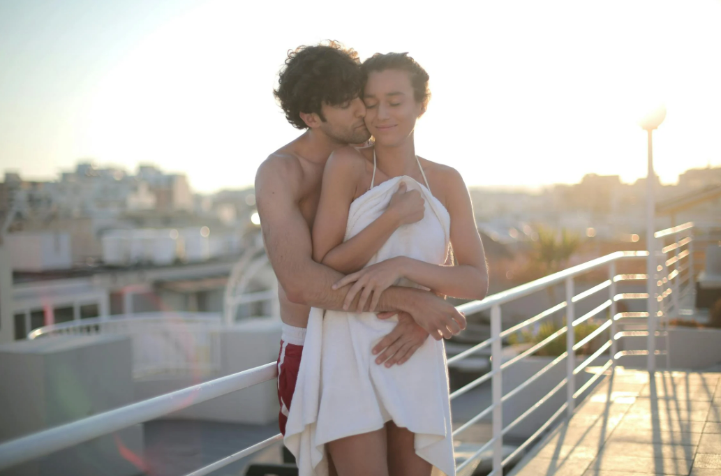 happy-lovers-embracing-on-rooftop-after-swimming-during-sunset