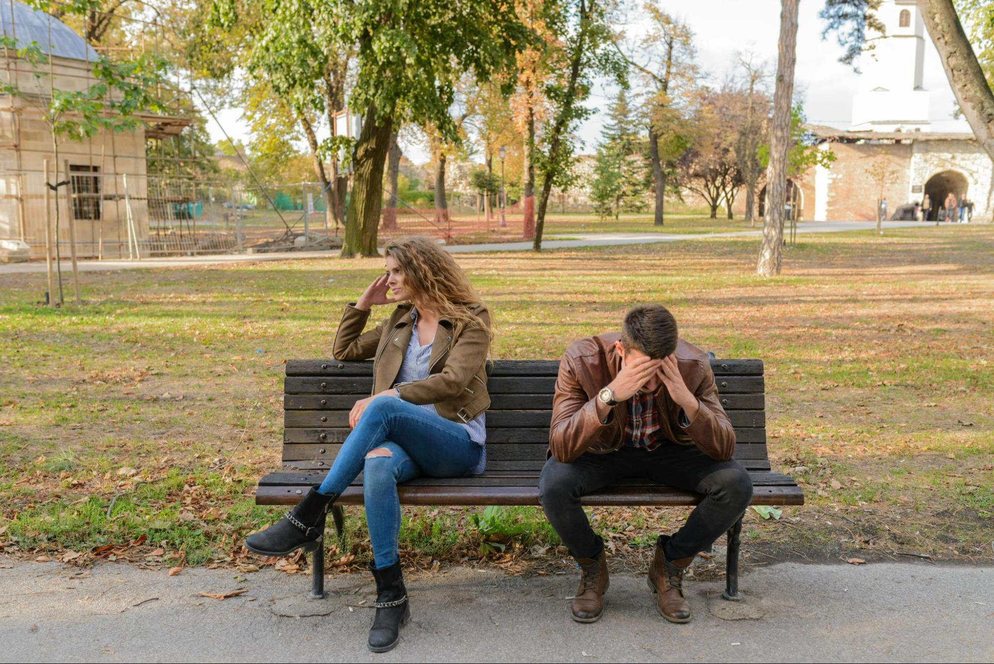 Woman-and-man-upset-sitting-on-brown-wooden-bench