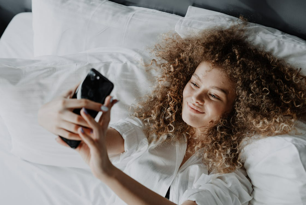 woman-in-white-button-up-shirt-lying-on-bed-sexting