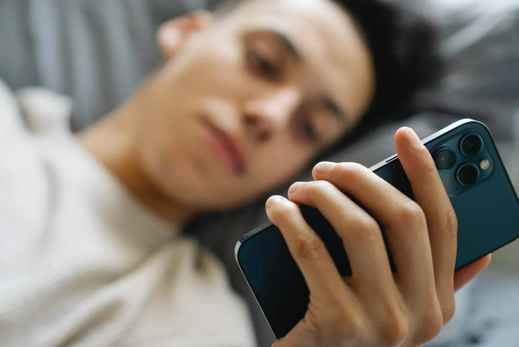 man-texting-partner-mobile-phone-on-bed