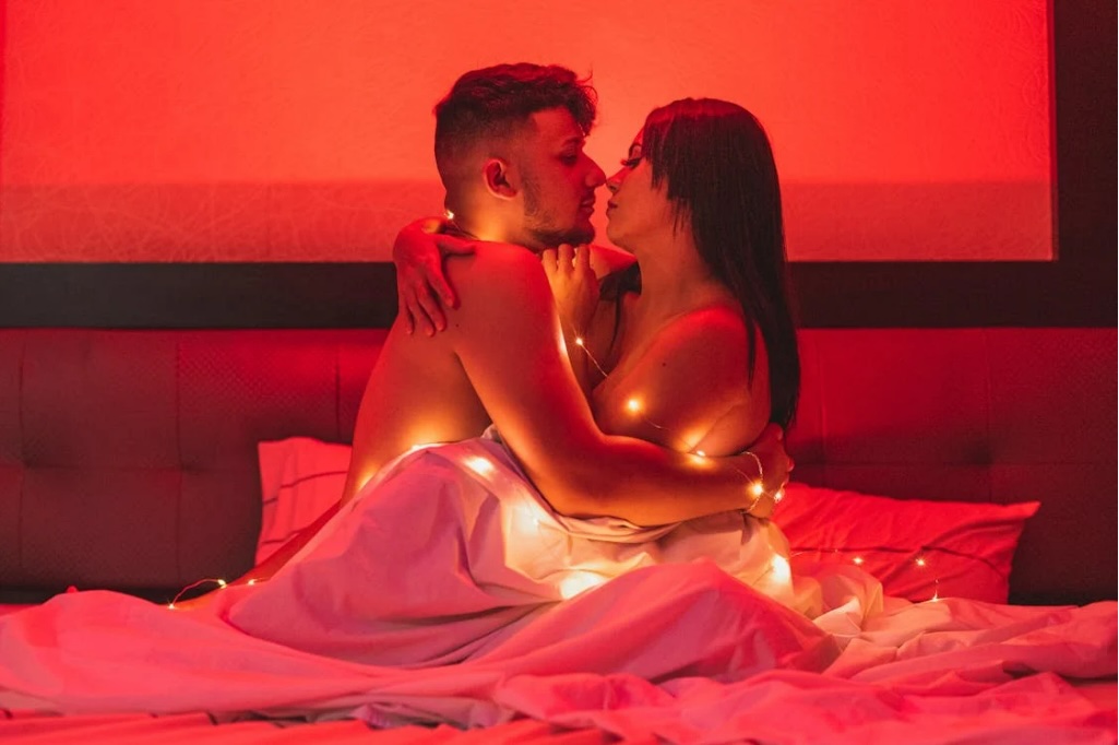 male-female-couple-being intimate-in-bed-red-lighting