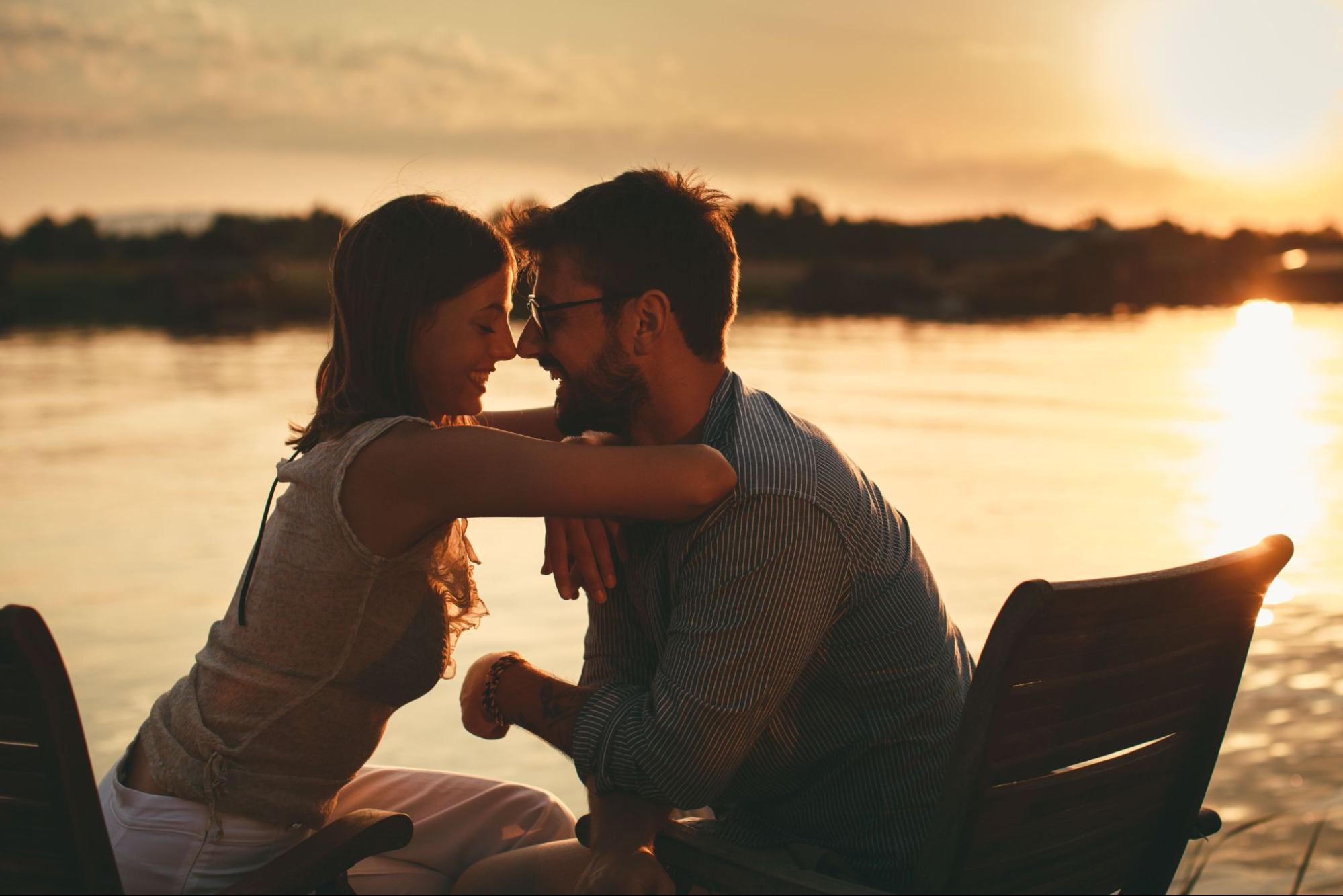 young couple flirting at lake during sunset date