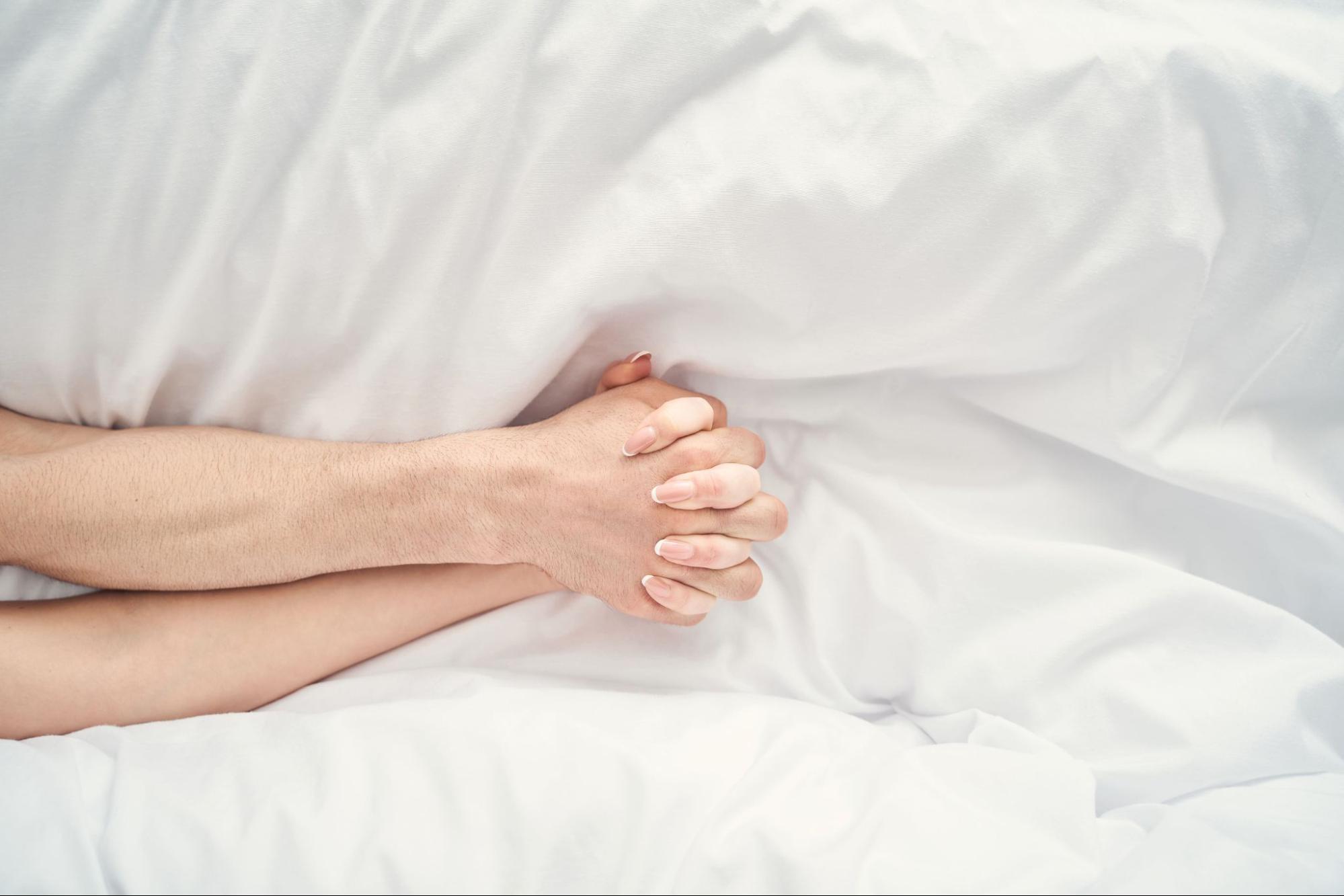 couple-holding-hands-during-mutual-orgasm-in-bed